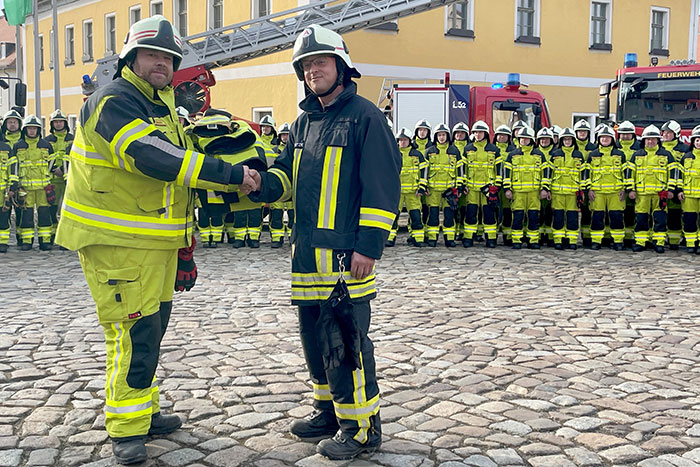 Gemeindewehrleiter Stefan Ullmann übergib die neue Einsatzbekleidung dem stellvertretenden Wehrleiter Frank Grützner aus Rückersdorf